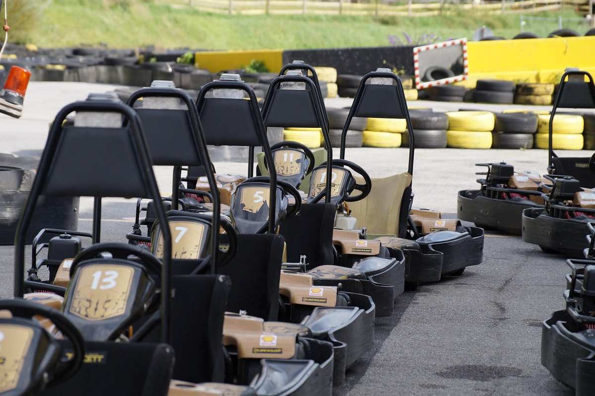 Rangée de karts garés sur une piste d'asphalte grise avec équipements en arrière-plan