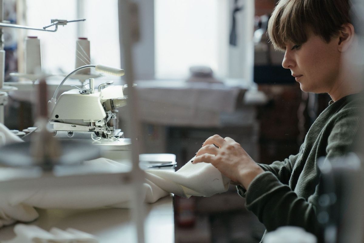 Femme travaillant sur un tissu avec une machine à coudre dans un atelier lumineux