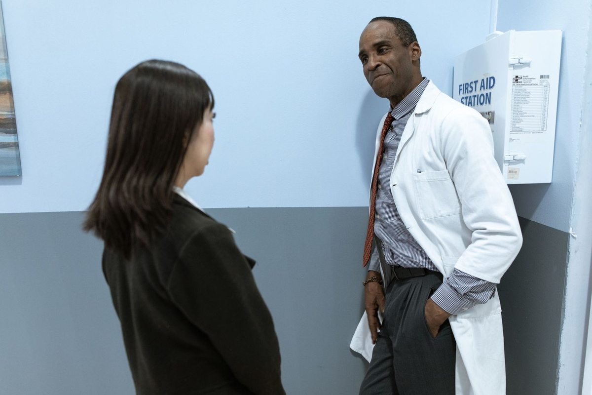 Homme en blouse blanche et femme en conversation dans un couloir médical