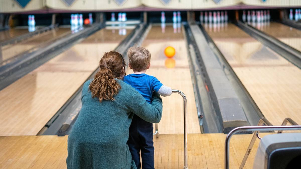 Une femme soutient un enfant qui regarde une boule jaune sur une voie