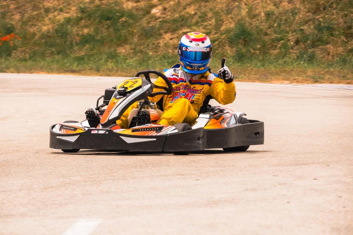 Un coureur de kart sur circuit donne le pouce avec son casque Un coureur de kart sur circuit donne le pouce avec son casque