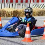 Enfant pilotant un kart bleu sur une piste de course miniature