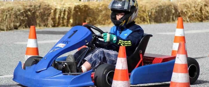 Enfant pilotant un kart bleu sur une piste de course miniature