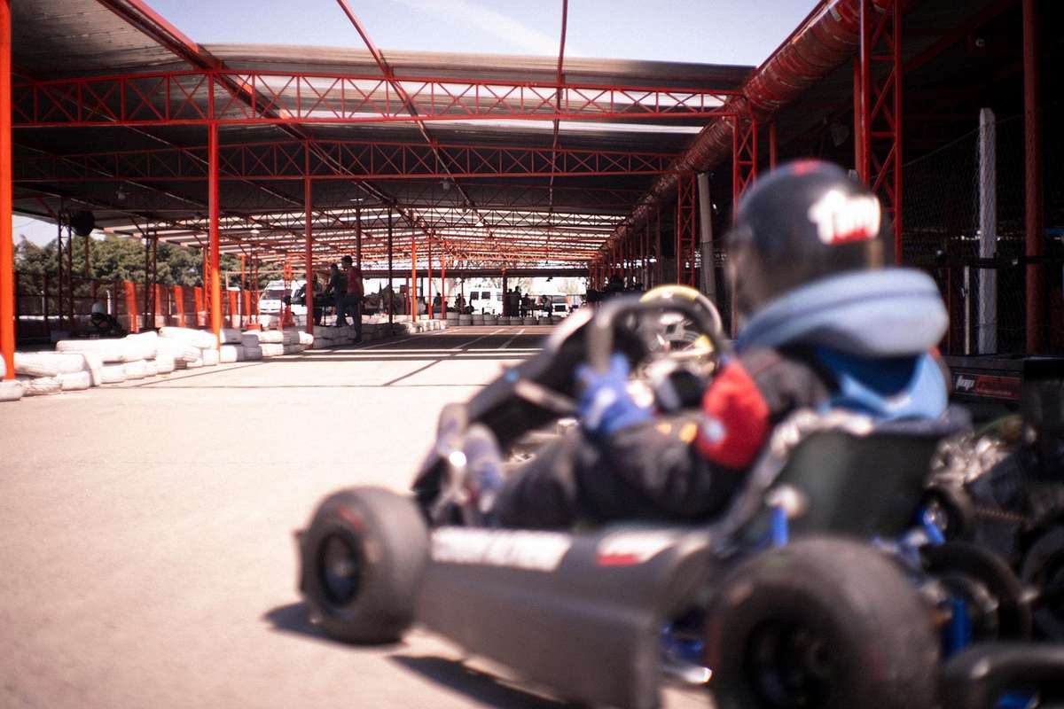 Un conducteur en kart sur piste couverte sous structure rouge