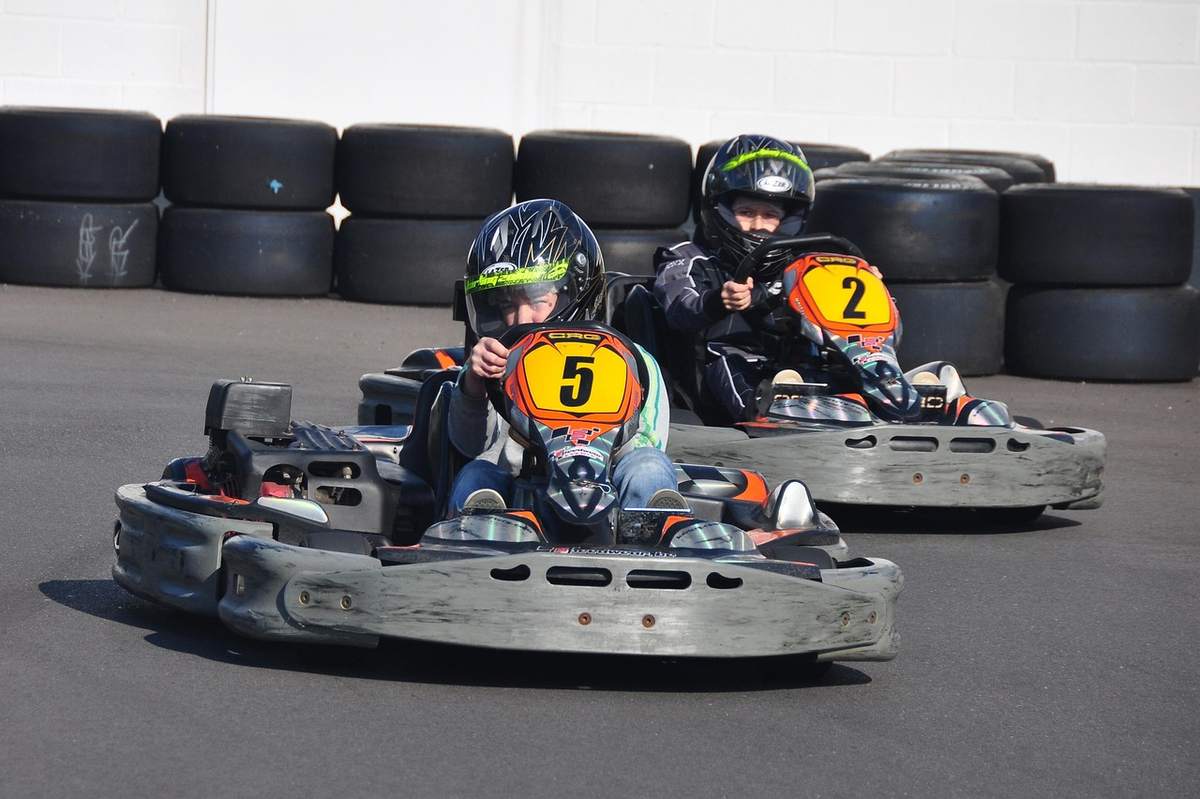 Deux enfants conduisent des karts numérotés 5 et 2 sur piste Deux enfants conduisent des karts numérotés 5 et 2 sur piste