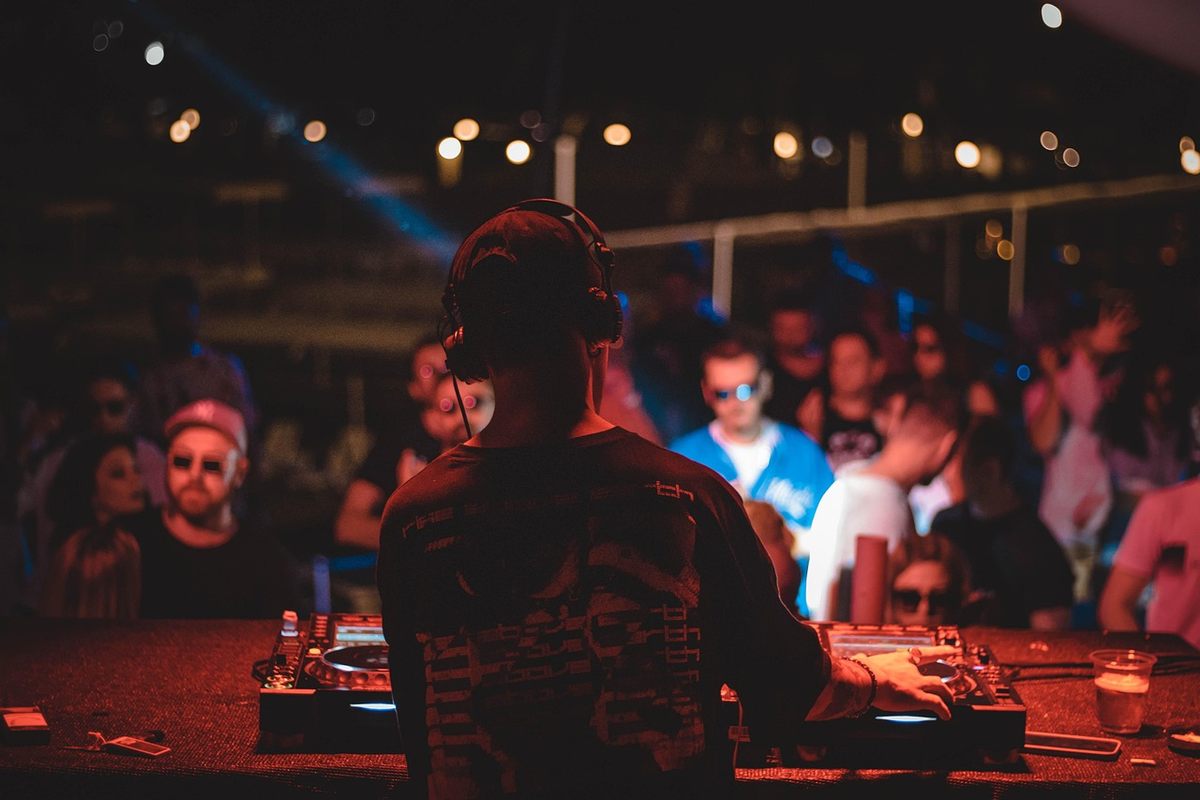 Un DJ mixe sur une platine devant une foule animée sous éclairage tamisé