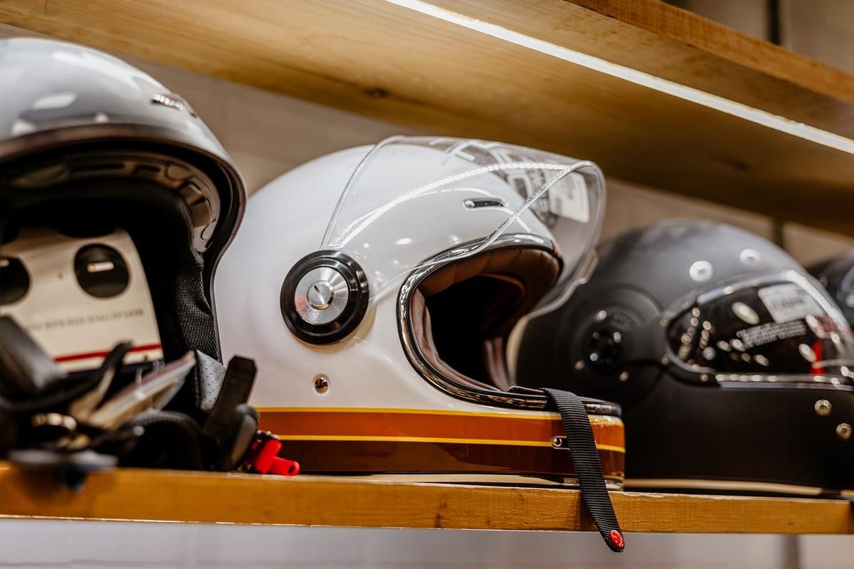 Trois casques de moto posés sur une étagère en bois Trois casques de moto posés sur une étagère en bois