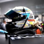 Un casque de course posé sur une voiture, gantée, stand de pit