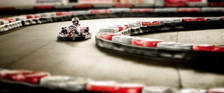 Un kart miniature tourne sur un circuit intérieur bordé de barrières